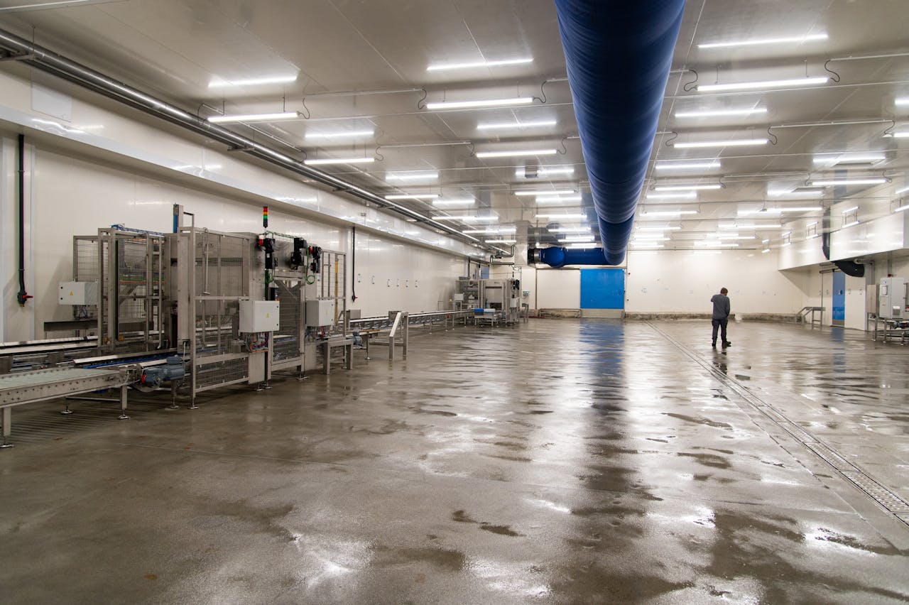 Spacious warehouse interior with machinery and a person inspecting the facility.